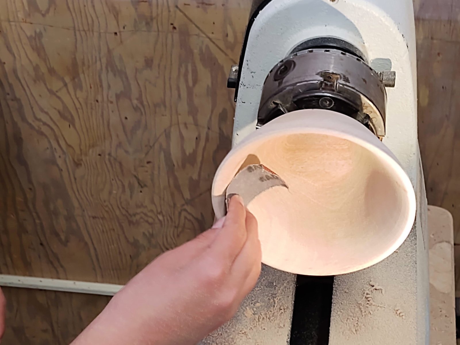 A student carefully hand sanding their bowl on the lathe.